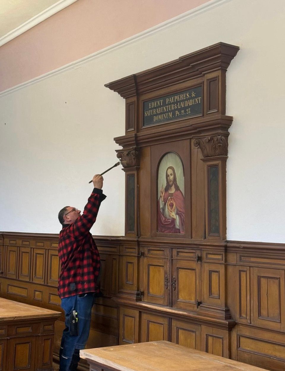 Restaurator bei der Arbeit an einem historischen Gemälde in einer Kirche